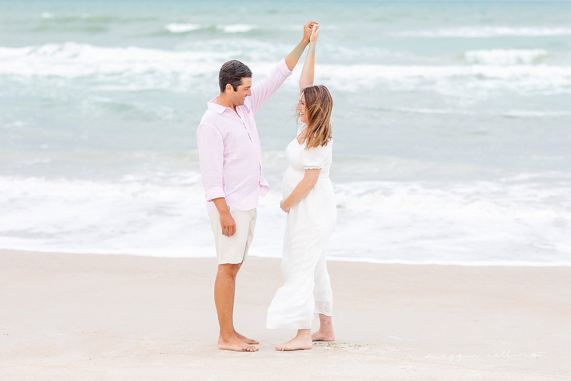 Maternity couple dancing on the beach.