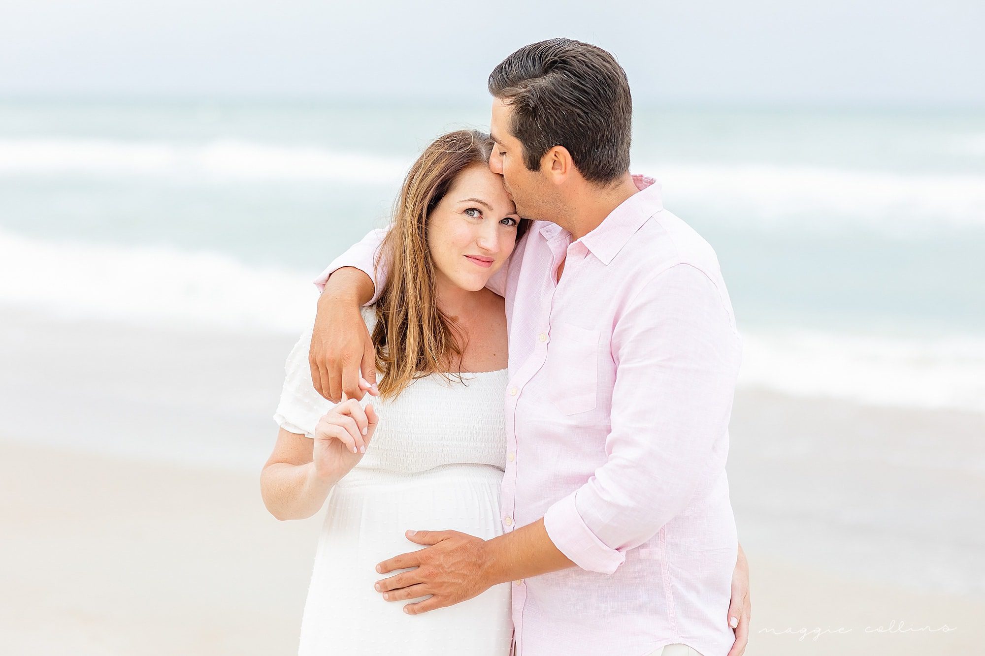couple embrace man kisses woman on the head maternity beach portrait