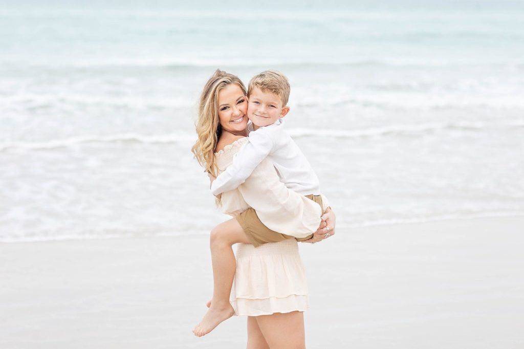Mom picks up her little boy and snuggles him up on New Smyrna Beach